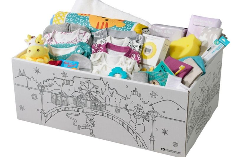 Scotland's baby box containing baby clothes, a blanket, a bath towel and a baby wrap, toys, bibs, a digital underarm thermometer and nursing pads